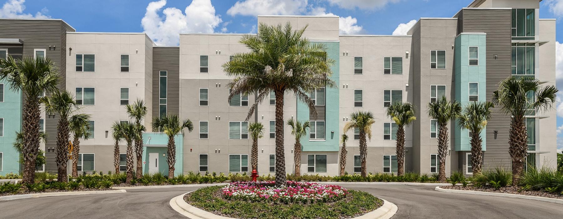 a building with palm trees and a road in front of it
